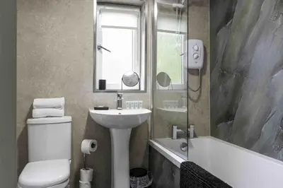 a bathroom with a sink and a toilet and a tub at Scotia House in Larkhall