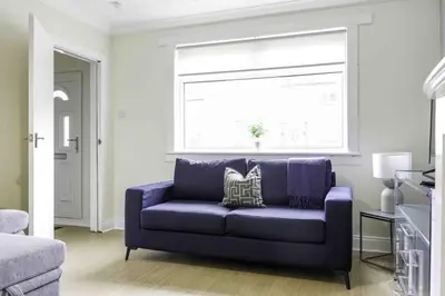 a blue couch in a living room with a window at Scotia House in Larkhall