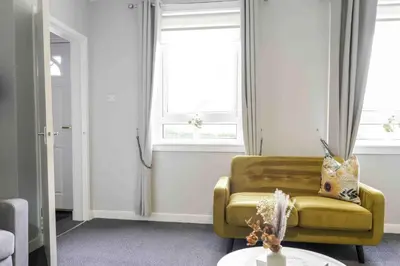 a living room with a yellow couch and a window at Pentland House in Bathgate