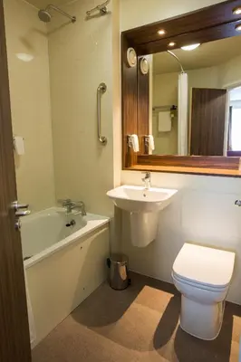 a bathroom with a sink and a toilet and a mirror at Queen of the Loch, Balloch by Marston's Inns in Balloch