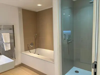 a bathroom with a shower and a tub and a sink at Stunning park view Quartermile apartment close proximity to Castle University in Edinburgh