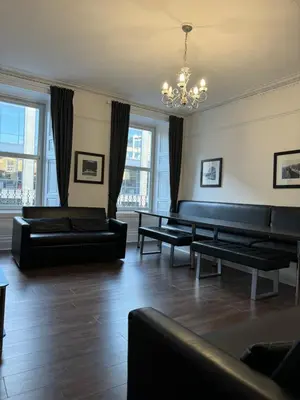 a living room with black leather furniture and windows at Central Morrison Street Apartment in Edinburgh