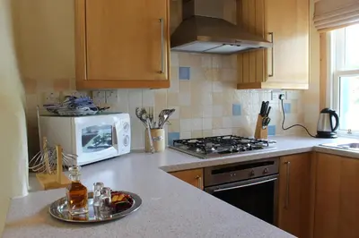 a kitchen with a stove and a microwave at Luss Cottages at Loch Lomond Arms Hotel in Luss