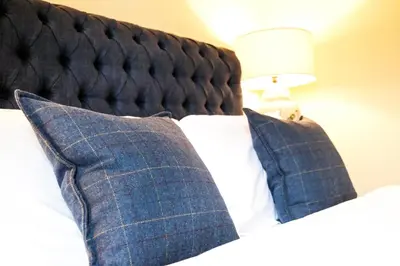 a bedroom with a bed with blue pillows at Luss Cottages at Loch Lomond Arms Hotel in Luss
