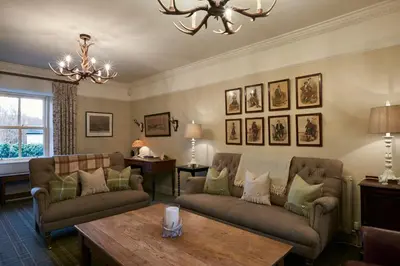 a living room with two couches and a table at Luss Cottages at Loch Lomond Arms Hotel in Luss