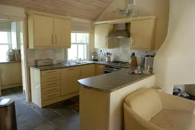 a kitchen with wooden cabinets and a counter top at Luss Cottages at Loch Lomond Arms Hotel in Luss