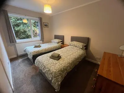two beds in a small room with a window at Lademill Cottage in Aberfeldy