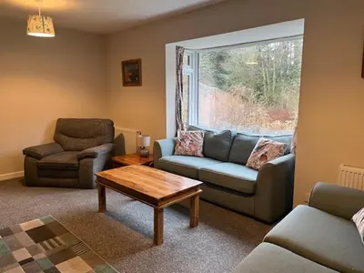 a living room with a couch and a chair and a table at Lademill Cottage in Aberfeldy