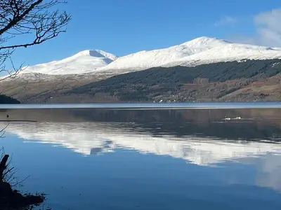a view of a lake with snow capped mountains in the background at Lademill Cottage in Aberfeldy