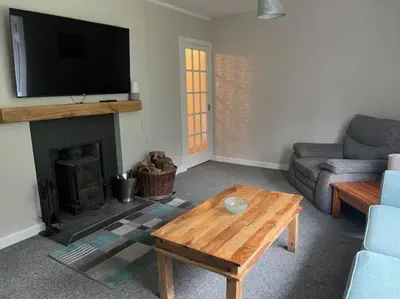 a living room with a couch and a table with a fireplace at Lademill Cottage in Aberfeldy