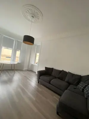 a living room with a black couch and wooden floors at 4 Smithhills Central 2 bed sleeps 4 in Paisley