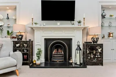 a living room with a fireplace with a tv above it at Stylish Murrayfield sanctuary in Edinburgh