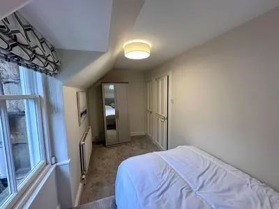 a bedroom with a white bed and a window at Stylish Murrayfield sanctuary in Edinburgh