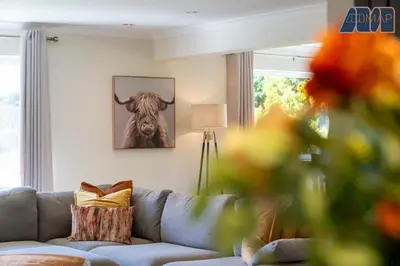 a living room with a couch and a picture of a cow at Large Family Home with Hot Tub or Jacuzzi, Log Burner in Bearsden