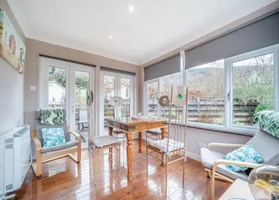 a living room with a table and chairs and windows at Picturesque beauty of Strachur in Strachur
