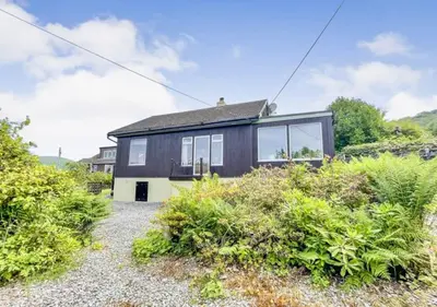 a black and white house with windows and bushes at Picturesque beauty of Strachur in Strachur