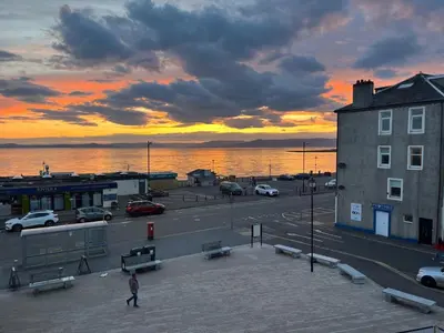 a person walking in a parking lot with a sunset at Largs 2 bedroom Apartment in Largs