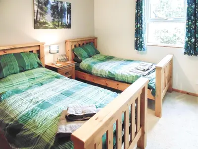 a bedroom with two beds and a window at Pine Cottage in Killin