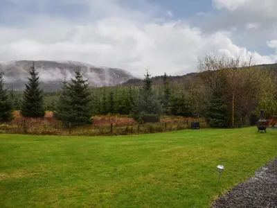 a green field with a mountain in the background at Pine Cottage in Killin