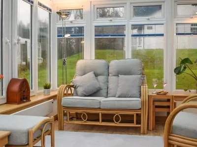 a room with a chair in front of windows at Pine Cottage in Killin