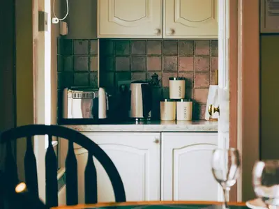 a kitchen with white cabinets and a table with a glass of wine at Lochy - Uk47884 in Keilour