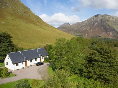 a white house in the middle of a mountain at Aonach Cottage - Uk41932 in Glencoe