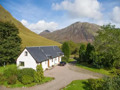 a white house in the middle of a mountain at Aonach Cottage - Uk41932 in Glencoe