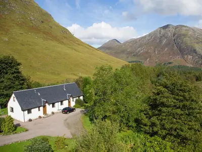a white house in the middle of a mountain at Bidean Cottage - Uk41933 in Glencoe
