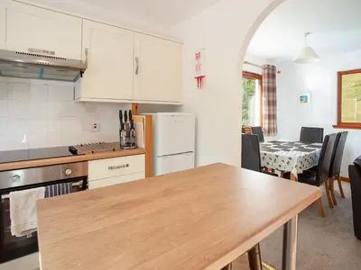a kitchen with a wooden table and a kitchen with a dining room at Bidean Cottage - Uk41933 in Glencoe