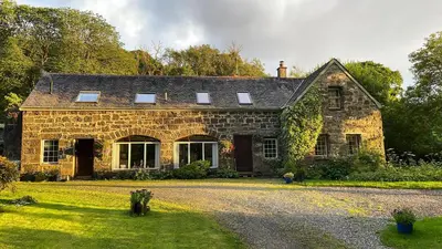 an old stone house with a driveway in front of it at The Coach House Knipoch in Oban
