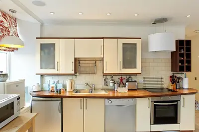 a kitchen with white cabinets and a wooden counter top at Crieff Armoury in Crieff