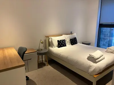 a bedroom with a bed with a desk and a window at Executive Quartermile apartment near to Castle University with park view in Edinburgh