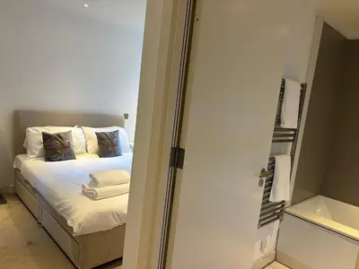 a bedroom with a bed with white sheets and pillows at Executive Quartermile apartment near to Castle University with park view in Edinburgh