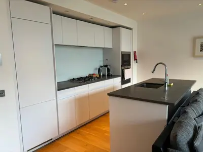 a kitchen with white cabinets and a black counter top at Executive Quartermile apartment near to Castle University with park view in Edinburgh