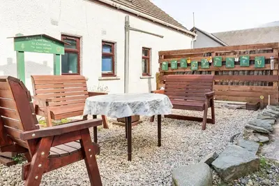 a patio with two benches and a table in front of a building at Lochranza Centre CIC in Lochranza