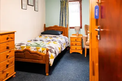 a bedroom with a bed and a dresser and a window at Lochranza Centre CIC in Lochranza