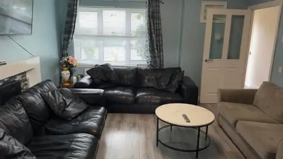 a living room with a leather couch and a table at Glasgow Central guest house free parking in Govan
