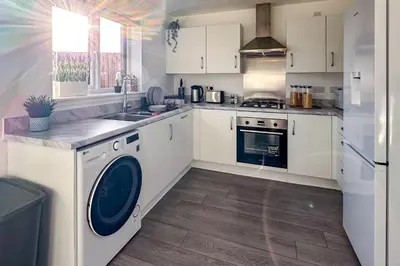 a kitchen with white cabinets and a washer and dryer at Newbuild Riverview 3BDR House near Glasgow in Dalmuir