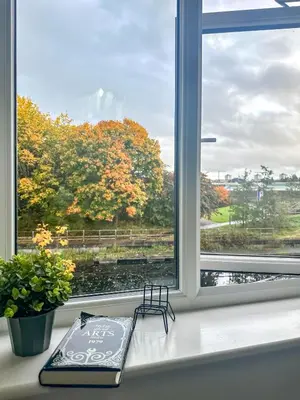 a book on a window sill with a view of trees at Newbuild Riverview 3BDR House near Glasgow in Dalmuir