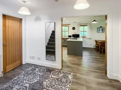 a living room with a staircase and a kitchen at Fin Glen in Killin