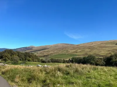 a field of grass with hills in the background at Fin Glen in Killin