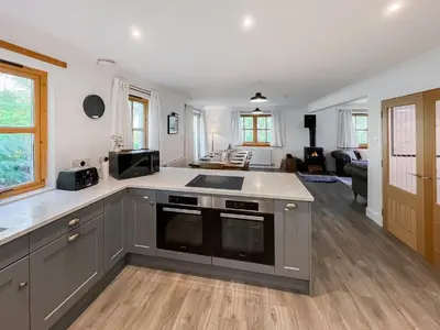 a kitchen with a counter top and a living room at Fin Glen in Killin
