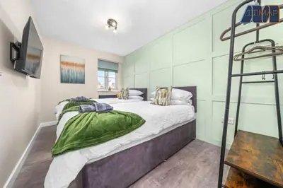a bedroom with a large bed and a television at Elegant 2Bed Sleeps 4 With Parking in Paisley