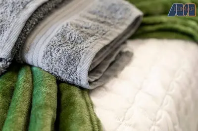 a pile of green and white towels on a bed at Elegant 2Bed Sleeps 4 With Parking in Paisley