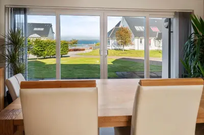 a dining room table with a view of the ocean at Stunning Sea Views - Luxury 4BR Beach House in Oban