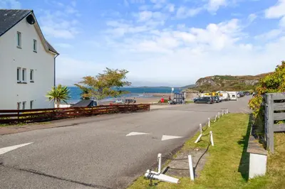an empty road with a house and the ocean at Stunning Sea Views - Luxury 4BR Beach House in Oban
