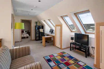 a living room with a couch and a tv at Stunning Sea Views - Luxury 4BR Beach House in Oban