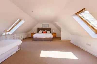 a attic bedroom with a bed and a window at The Stables at Brickrow Farm in Ayr