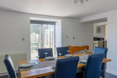 a dining room with a wooden table and blue chairs at The Stables at Brickrow Farm in Ayr