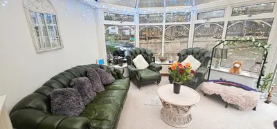 a living room with two green couches and a table at Boghead Cottage The West Wing in Bathgate